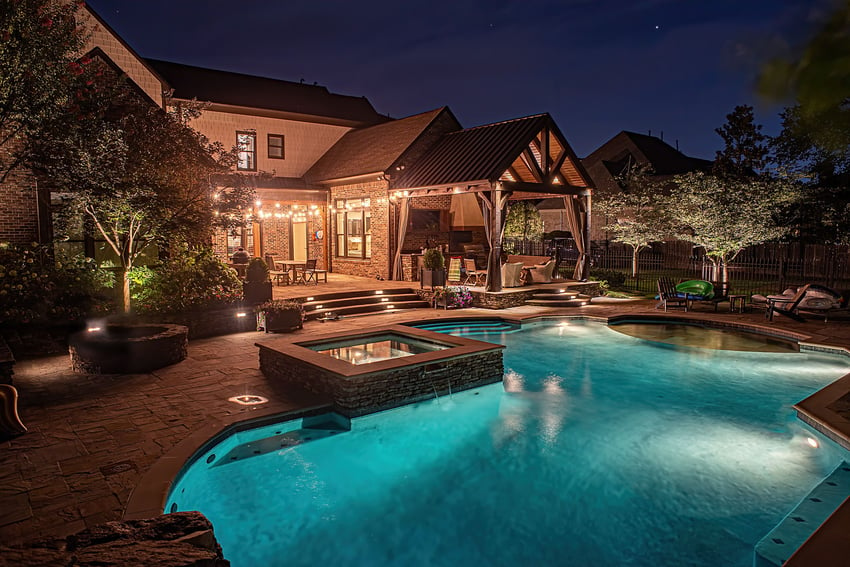 backyard with covered outdoor kitchen, pool, and lighting