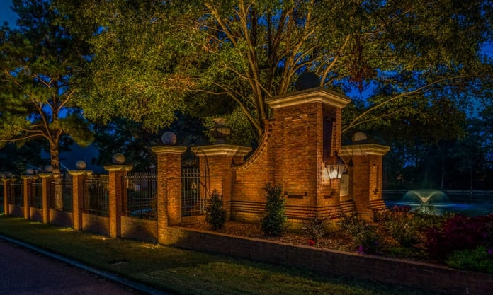 Commercial landscape lighting neighborhood entrance brick fence uplighting