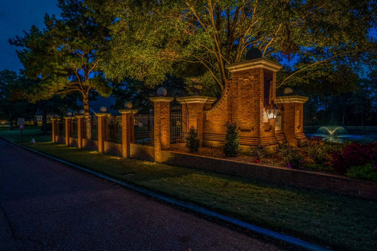 Commercial landscape lighting neighborhood entrance brick fence uplighting