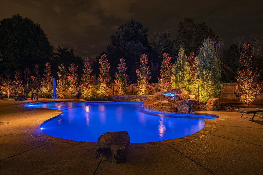 Pool surrounded by landscape lighting at night